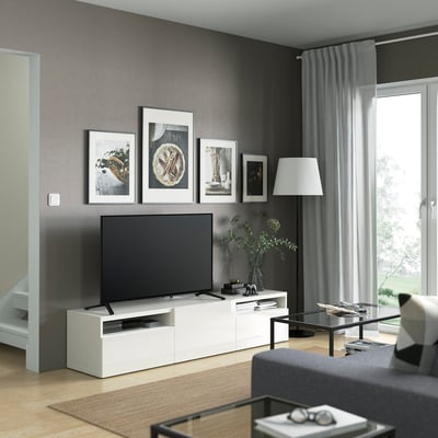 Sala de estar moderna con soporte de televisión SELSVIKEN, televisión, fotos enmarcadas, lámpada, mesa de café de vidro e sofá gris.