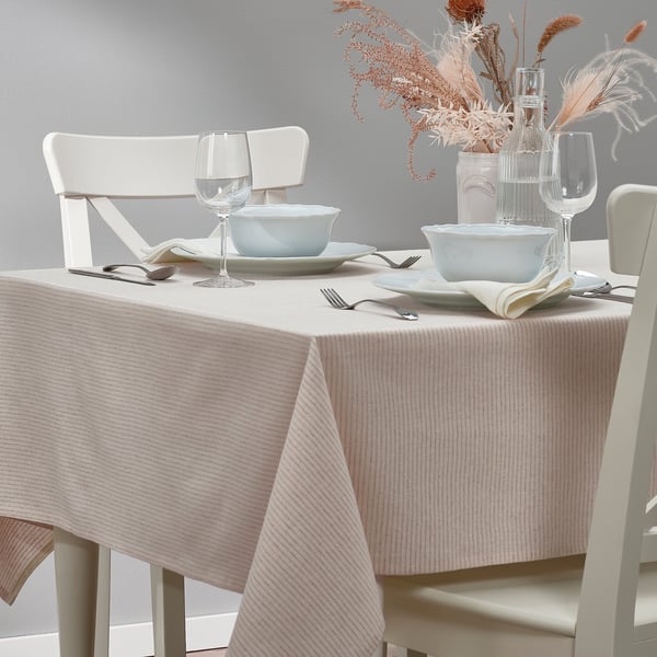 Mesa con cadeiras e cuncas brancas, vasos e vasos decorativos sobre un pano de mesa de raias beige.