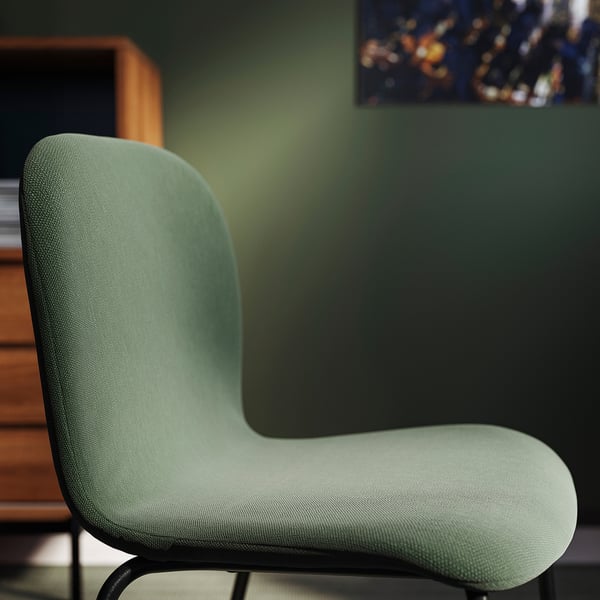 Cadeira tapizada verde menta moderna, ben acolchada, con base metálica elegante contra a parede verde.