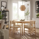 Comedor moderno con mesa e cadeiras de madeira SKANSNÄS, madeira clara, forma redonda, deseño escandinavo, luz colgante, plantas, estantes.