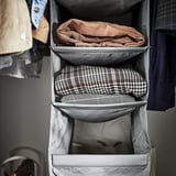 Organizador de armario gris SKUBB que sostén roupa dobrada.