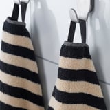 Dúas toallas a raias colgan ordenadamente nos ganchos, mostrando o seu deseño absorbente e elegante.