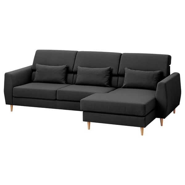 Sofá gris escuro en forma de L con pernas de madeira, costas altas e almofadas decorativas.