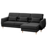 Sofá gris escuro en forma de L con pernas de madeira, costas altas e almofadas decorativas.