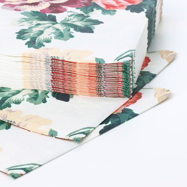 Servilletas con patróns florais, de tres capas, apiladas ordenadamente, mostrando durabilidade e absorción.