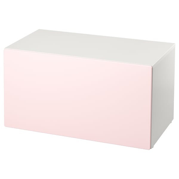 Un banco de almacenamento de smastad en rosa claro e branco. Forma rectangular, deseño sinxelo, ideal para o almacenamento de xoguetes.