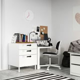Habitación moderna para nenos con peito e escritorio branco SMÅSTAD, cadeira negra, decoración colorida, alfombra a raias e reloxo grande.