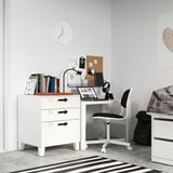 Pequeno escritorio branco no dormitorio con cadeira negra, libros e reloxo. Deseño moderno e minimalista.