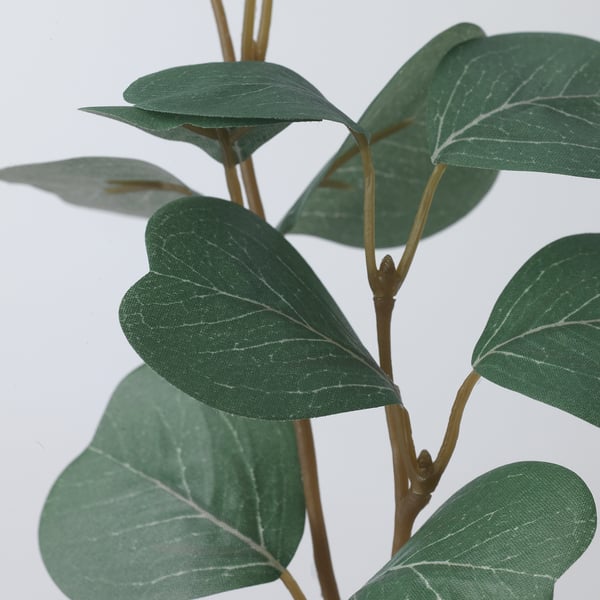 Primeiro plano de planta artificial realista, follas verdes vibrantes unidas ao talo flexible.