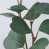 Primeiro plano de planta artificial realista, follas verdes vibrantes unidas ao talo flexible.