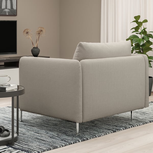 Sofá gris claro con coxíns de peluche e altas patas metálicas. Mesa lateral con cunca de café e libro.