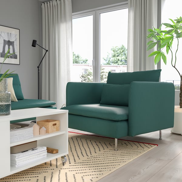 Sala de estar con cadeira de brazos SÖDERHAMN verde azul, sofá, plantas, estantes, alfombra e grandes fiestras.