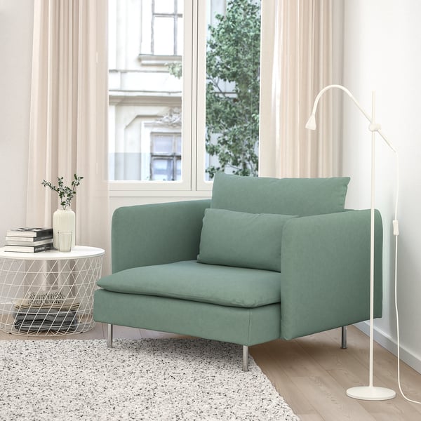 Sala de estar moderna con cadeira de brazos verde SÖDERHAMN, patas metálicas, lámpada de chan branca, chan de faia, alfombra, mesa lateral e vista á fiestra. - Cadeira de brazos dominante.