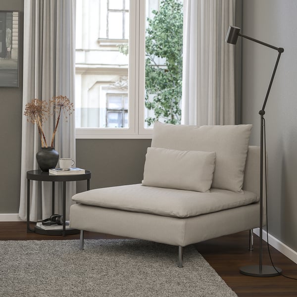 Cadeira minimalista moderna SÖDERHAMN, beige, tecido suave, perfil baixo. Preto de lámpada de chan, mesa lateral con vaso e cunca, gran fiestra. Recuncho acolledor.