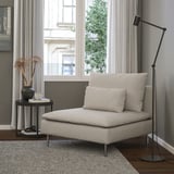 Cadeira minimalista moderna SÖDERHAMN, beige, tecido suave, perfil baixo. Preto de lámpada de chan, mesa lateral con vaso e cunca, gran fiestra. Recuncho acolledor.