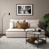 Sala de estar moderna con sofá SÖDERHAMN beige, coxíns, lámpada negra, mesa de café de vidro e planta verde.