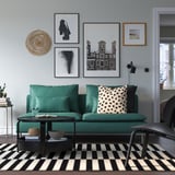 Sala de estar moderna con sofá verde SÖDERHAMN, mesa de café negra, alfombra a raias e galería de arte de parede.