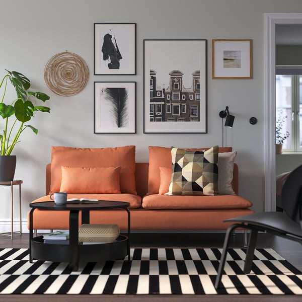 Sala de estar moderna con sofá laranxa SÖDERHAMN, decoración en branco negro e arte abstracta.