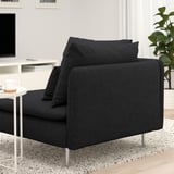 Sofá negro moderno con coxíns. Ofrece asentos profundos e relaxados e coxíns de apoio. Colocado xunto a unha pequena mesa cunha cunca de café.
