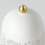Lámpada elegante con intrincada base floral, brillante parte superior de esfera dourada, proxecta luz suave.