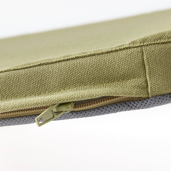 Primeiro plano dun coxín con cremalleira, beige-verde cobre o bordo, mostrando costuras de calidade e tecido resistente.