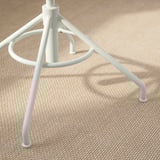 Base de cadeira metálica, acabado branco, tres patas de trípode e pau central, sobre chan beige texturizado.