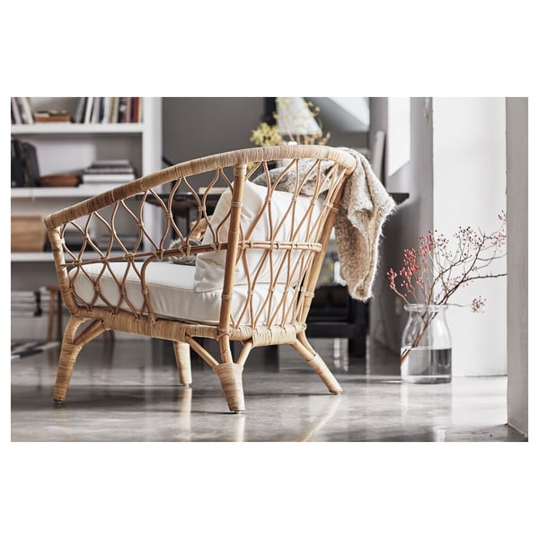 Cadeira de vimbio moderna en cor natural con coxíns, situada nunha habitación minimalista.