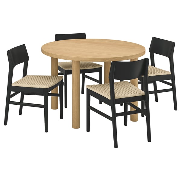 Conxunto de comedor moderno con mesa redonda de revestimento de carballo recheo de favo de mel e catro cadeiras negras de vimbio, ideal para reunións acolledoras.