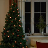 Unha árbore de Nadal adornada con luces de corda alimentadas por batería en forma de pequenos agasallos, creando unha atmosfera festiva e cálida.
