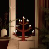 Candelabro vermello con lámpadas led na xanela, creando unha atmosfera cálida e acolledora.