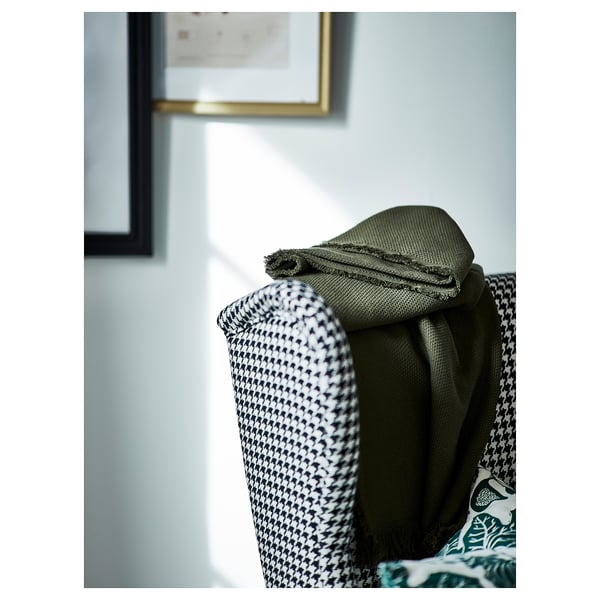 Luxoso tecido verde envolto sobre unha elegante cadeira con patrón de houndstooth, facendo fincapé no confort e o deseño de alta calidade.