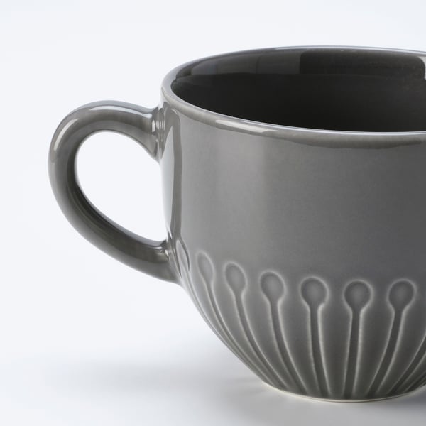Cunca de cerámica gris escuro cun mango suave e patrojo floral texturizado preto da base. Acabado acristalado, deseñado cun aspecto moderno e limpo.