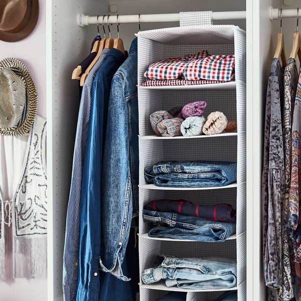Armario organizado con roupa azul e estantes de almacenamento colgantes brancos, parte da serie STUK.