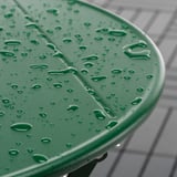 Mesa exterior de plástico verde con gotas de auga, pregamentos para almacenamento.