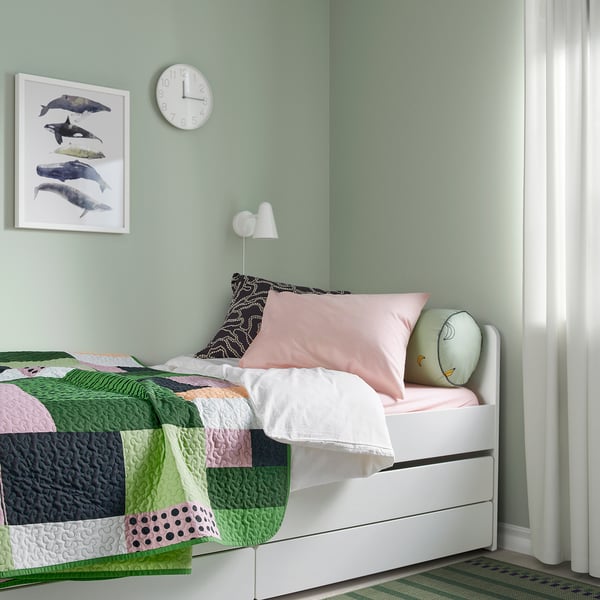 Cuberta de cama de patchwork colorido en cama xemelga, paredes verdes claras, arte de golfiños, almofadas rosas e curuxas, deseño minimalista.