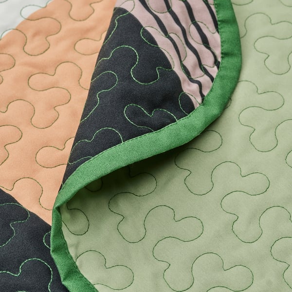 Primeiro plano de TALLSVÄRMARE patchwork en verde, destacando tecidos suaves e reciclados con patróns intrincados.