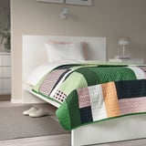 Gran cuberta de cama quilted multicolor cobre a cama, cabeceira branca, almofadas pastel.