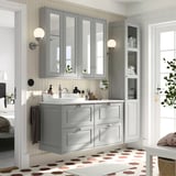Vanidade gris TÄNNFORSEN con lavabo, caixóns, armarios con espellos, paneis bisesiños, sconces de parede, chan xeométrico de baldosas.