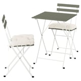 Unha mesa e cadeiras ao aire libre brancas e plegables con coxíns suaves, ideal para espazos compactos.