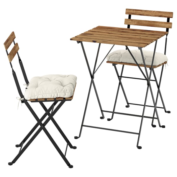Dúas cadeiras plegables con coxíns e unha mesa plegable, tapas de madeira, marcos metálicos negros. Conxunto de mobles de exterior compactos.