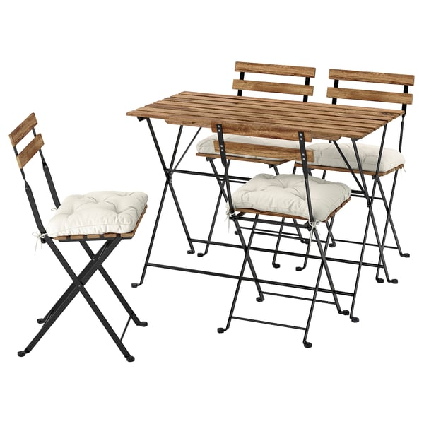 Patio exterior con mesa de madeira e 4 cadeiras. As cadeiras teñen coxíns brancos, marcos metálicos negros.
