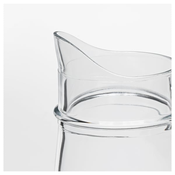 Xerra de vidro transparente cun mango curvo, superficie lisa e boca ancha, ideal para servir bebidas ou como vaso.