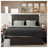 Dormitorio moderno con cabeceira TJÅLLE negra, roupa de cama gris e estantes de madeira.