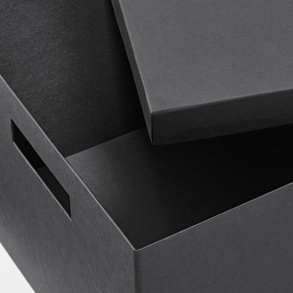Caixas de cartón negro apiladas con mangos recortados. Material robusto e reciclado. Ordenado e organizado.