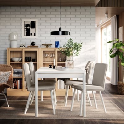 Comedor minimalista con mesa branca, cadeiras grises, sideboard de madeira e luz colgante negra.