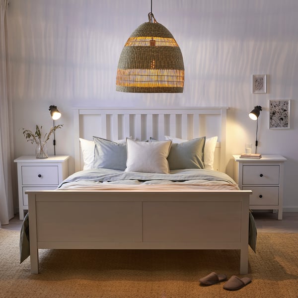 Dormitorio acolledor con cama branca, lámpada TORARED e mesas de noite.