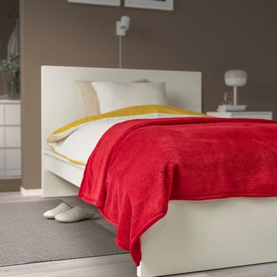 Cama con manta vermella TRATTVIVA, almofadas brancas e mesa de noite. Suave, grande e acolledora.