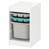 Unha unidade de almacenamento branca TROFAST con bandexas turquesa e gris escuro e unha caixa de almacenamento gris.