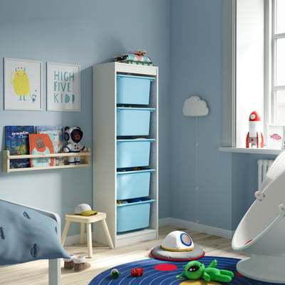 Habitación infantil con xoguete azul TROFAST e almacenamento de libros, marco branco, estante de parede, arte de monstros.