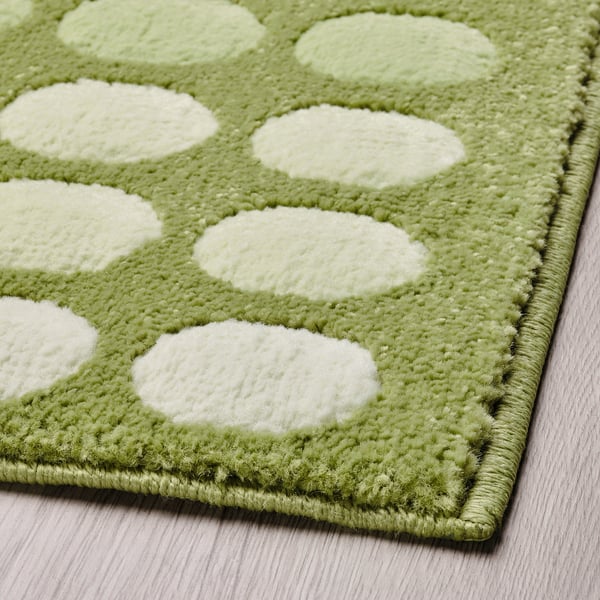 Alfombra de porta punteada verde e branca, textura suave, colocada nun chan de madeira.